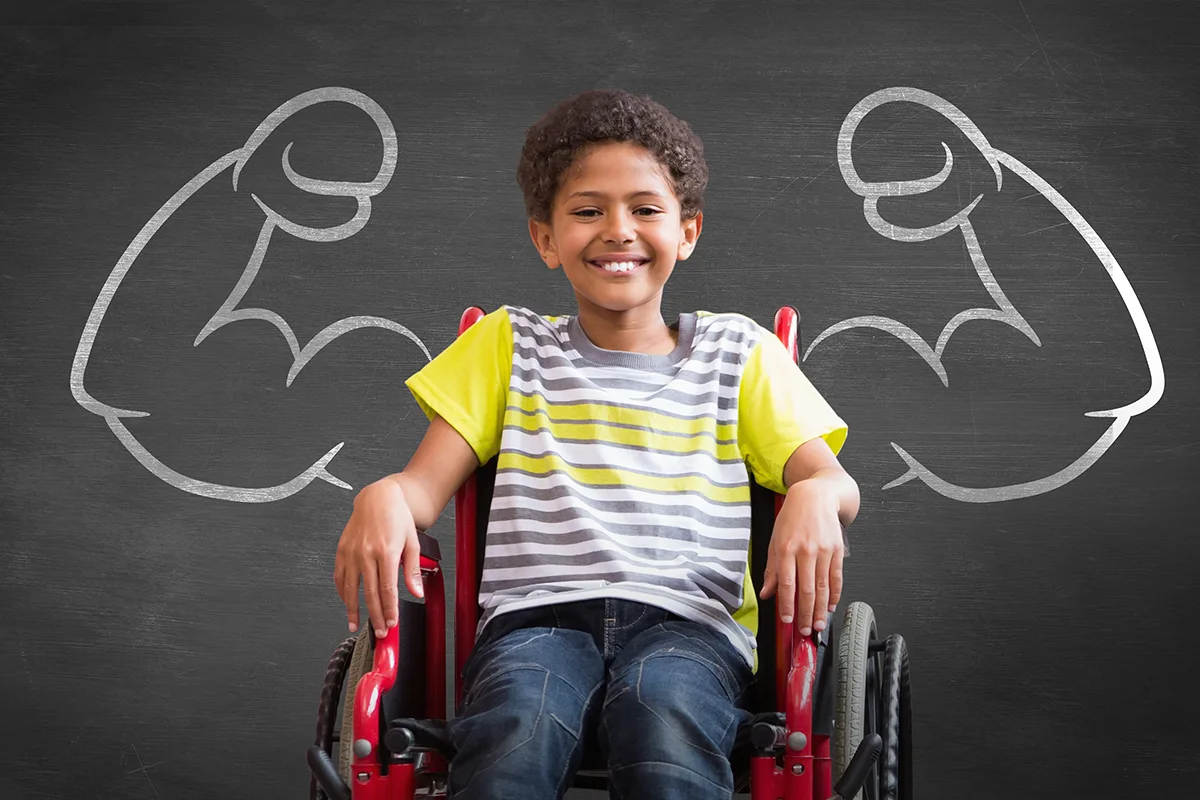 Image of a child in a wheelchair with a drawing of boxer arms on a chalkboard